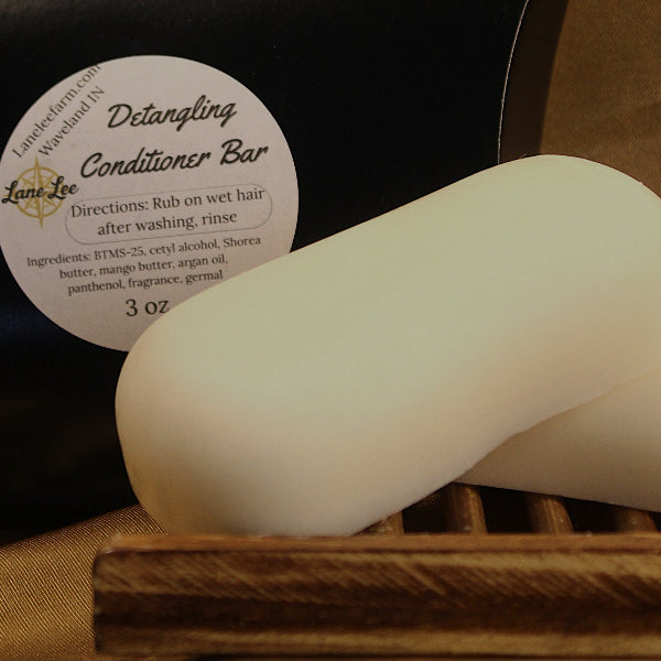 Two white soap bars on a wooden tray with a label in the background.